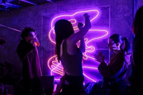 Neon Lights at a night club man drinking , woman clapping and dancing