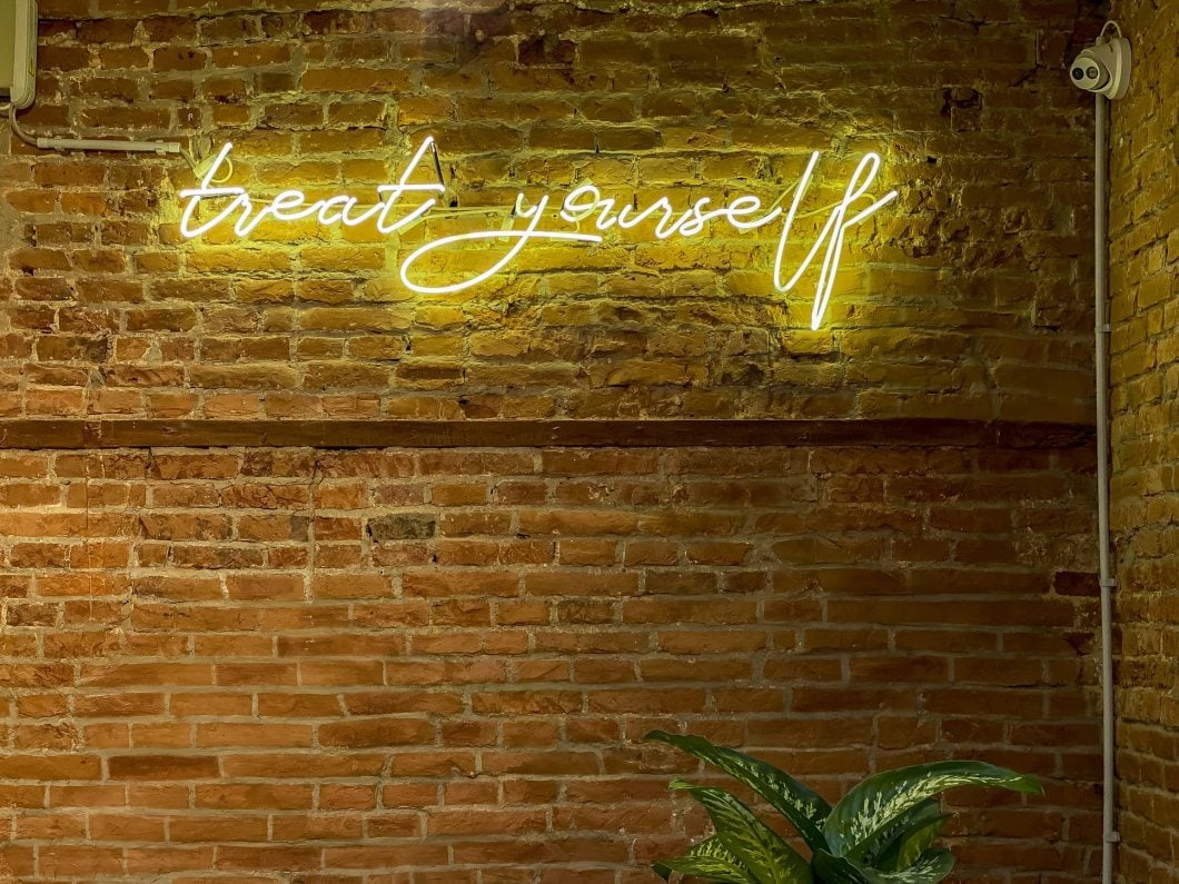 Trat yourself yellow neon lights on a brick wall background